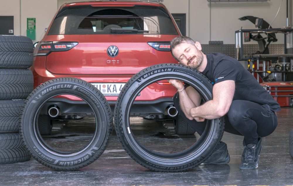Jonathan Benson avec deux pneus Michelin devant une Volkswagen Golf GTI d’essai