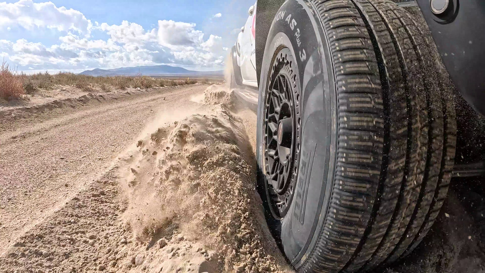 Pneu Pirelli Scorpion AS Plus 3 projetant du sable meuble à côté d'un Ford Ranger Raptor